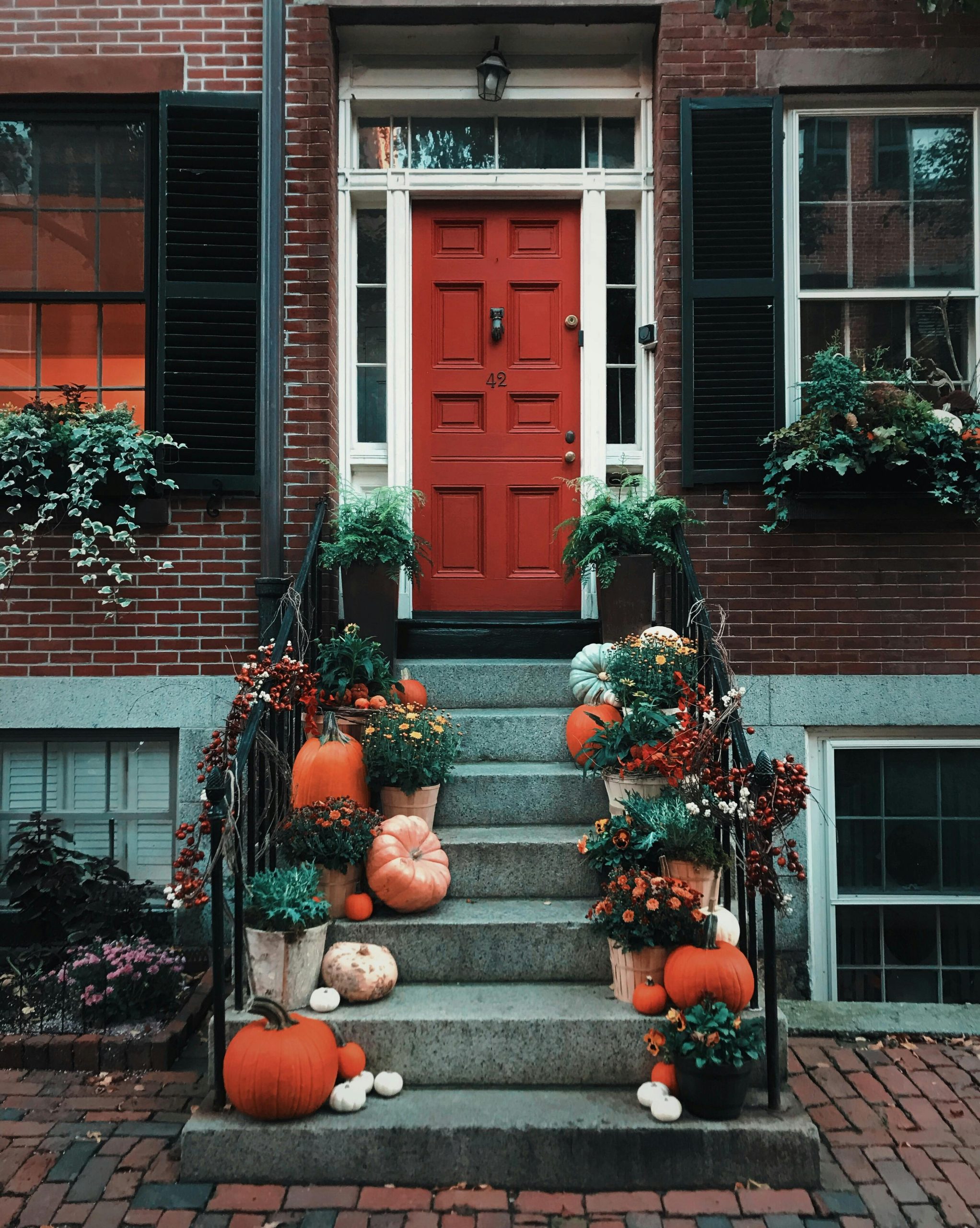 Front door styled for fall with buffalo check rug, Hello Pumpkin doormat, and neutral wreath.