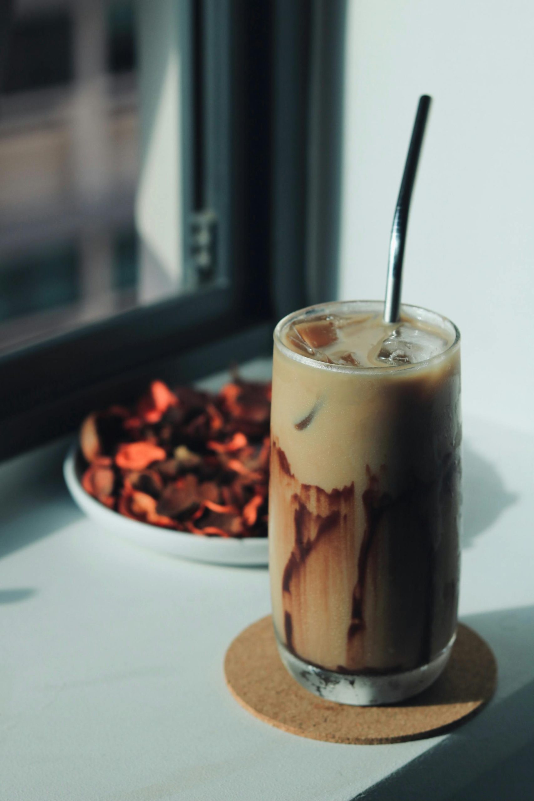 Iced coffee in a glass with straw on a fall morning