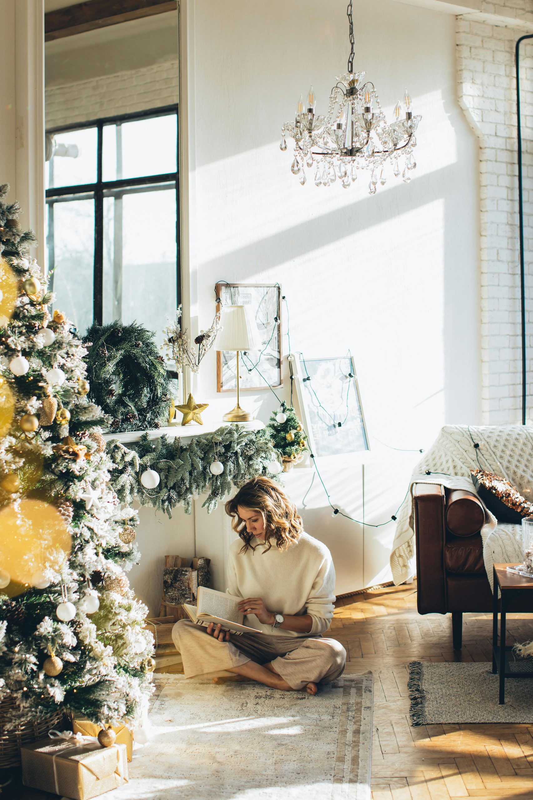 Cozy holiday living room with fluffed pillows, folded throws, and softly lit Christmas tree.